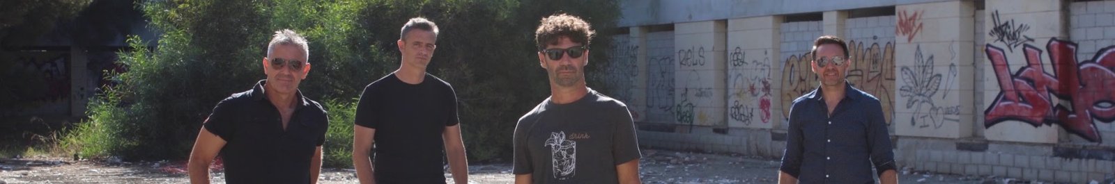 Los Cucas de pie en un solar con grafitis, a la luz del sol