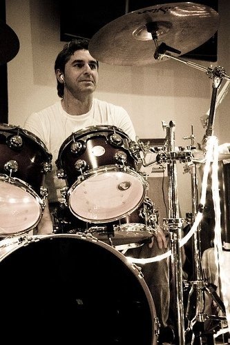Baterista de Los Cucas tocando en un local de ensayo, en sepia
