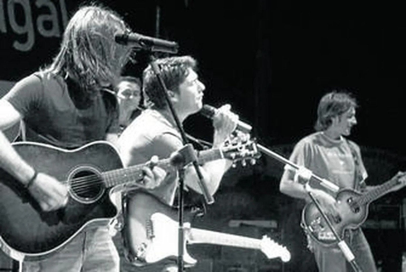 Foto en blanco y negro de Los Cucas en directo con guitarras y micrófonos